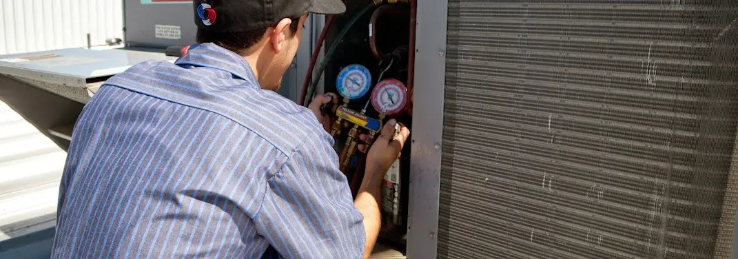 HVAC technician servicing a condenser unit in Graham